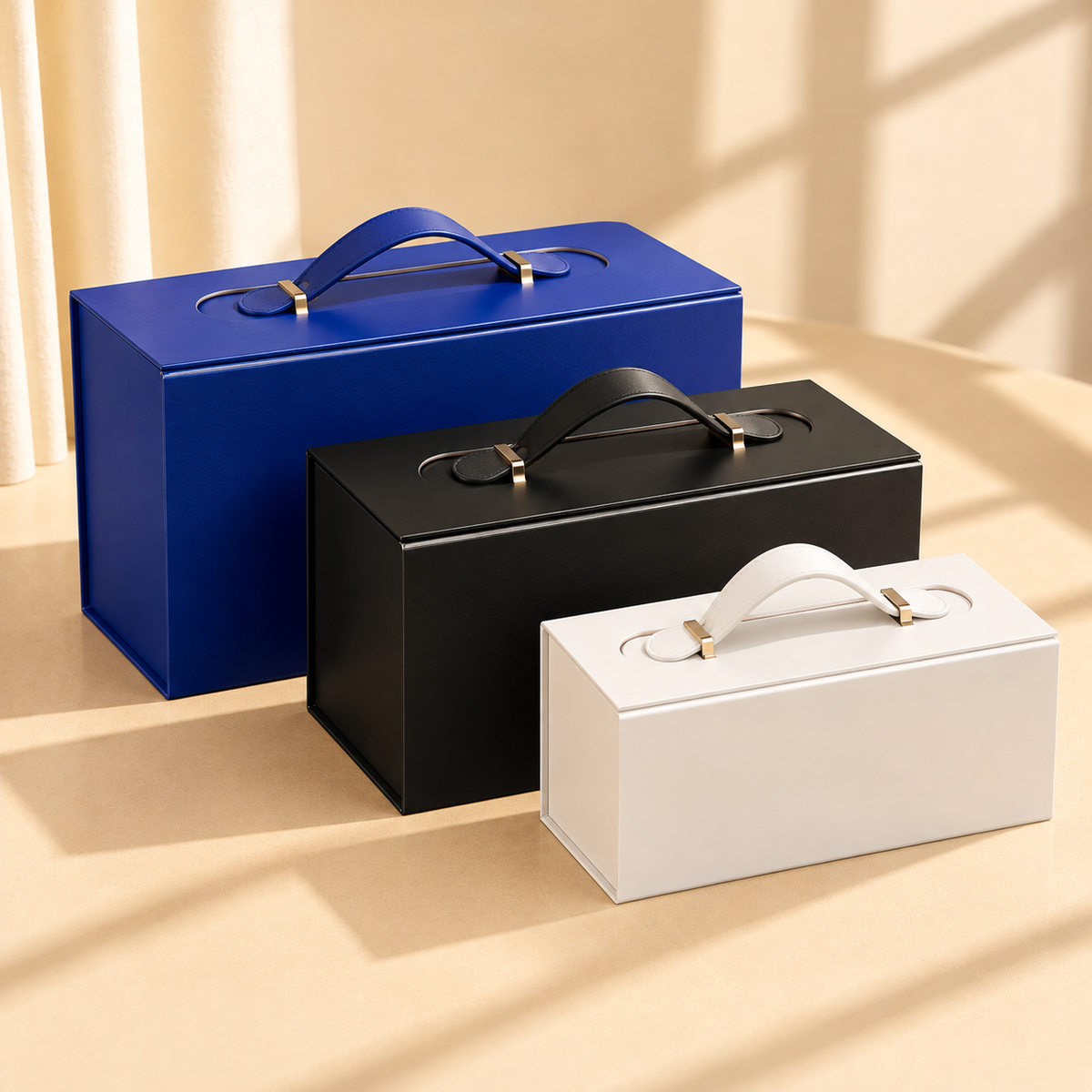White, black and blue magnetic folding gift boxes with handles shown in three sizes for comparison.