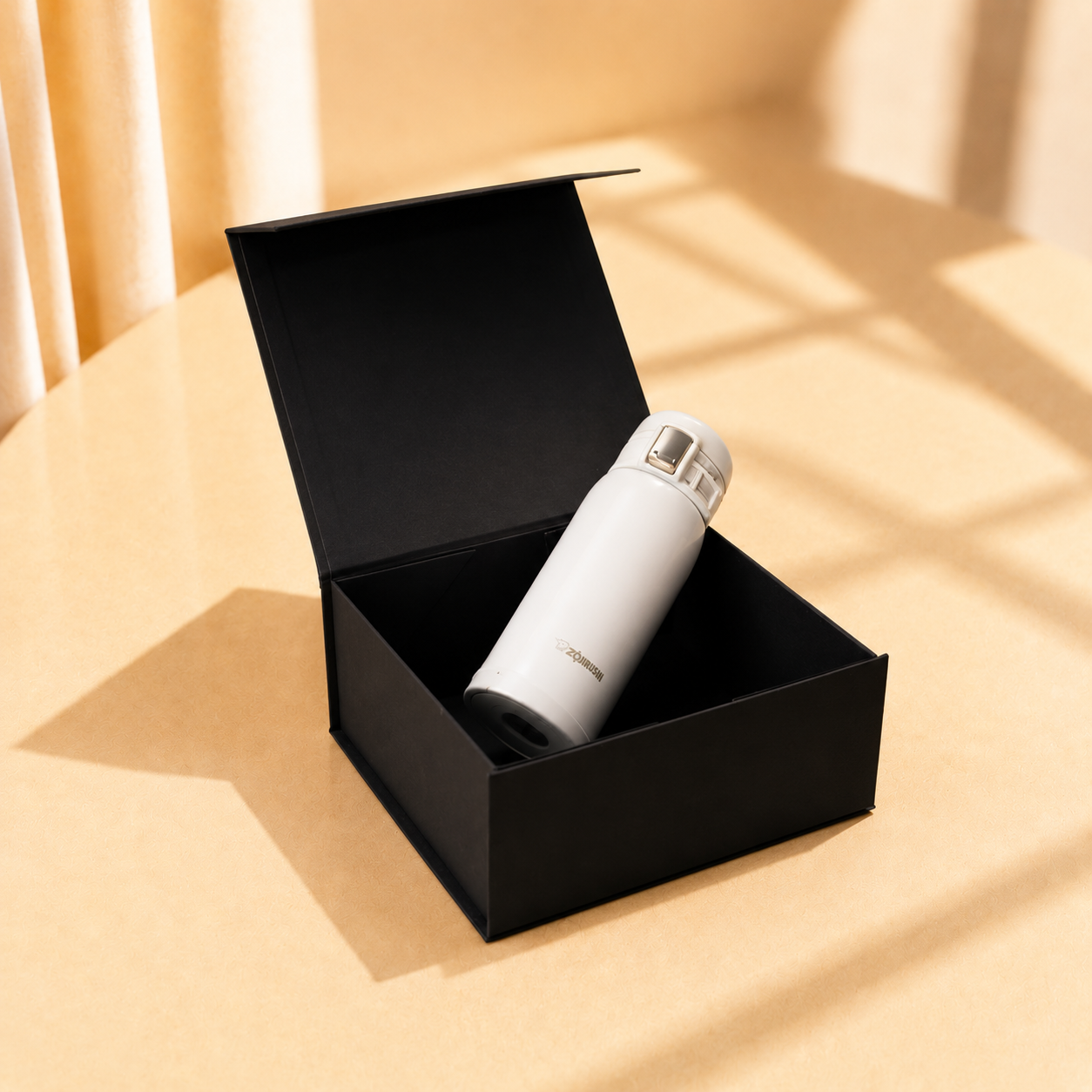 Open black rigid gift box holding a white bottle