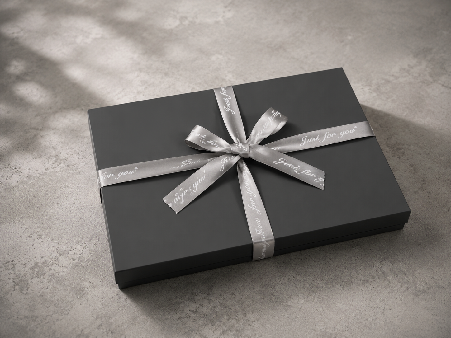 Top-down interior view of an open luxury gray gift box, showing custom-cut velvet slots designed to perfectly hold an executive pen, notebook, and electronic pulse lighter.