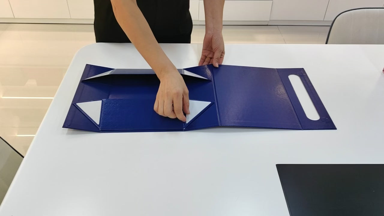 Blue collapsible luxury gift box being assembled from a flat panel