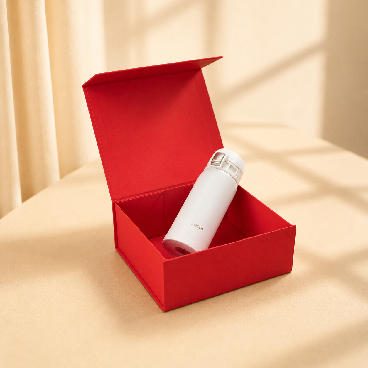 Open red magnetic gift box holding a white bottle